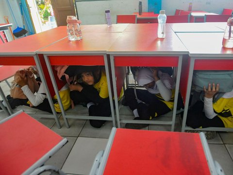 FOTO: Ekspresi Siswa SD di Depok Ikuti Simulasi Gempa, Panik dan Berlindung di Kolong Meja