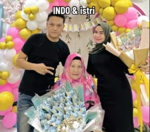 Anak ketiga dari ibu berhijab pink ini memiliki nama Indo. Kompak bersama istrinya, Indo mengenakan buana berwarna hitam. Keduanya berfoto bersama ibu dengan bahagia.