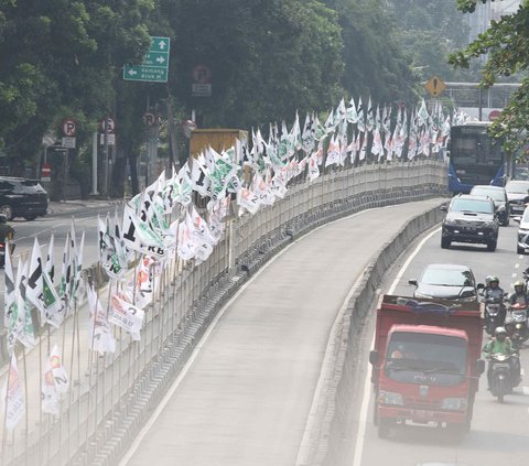 Meskipun masa kampanye belum dimulai, keberadaan atribut bendera partai pada pembatas jalan bisa saja membahayakan pengguna jalan.