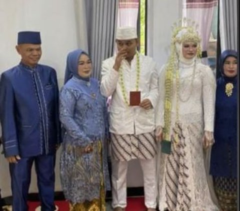 Pasangan ini mengenakan baju pengantin warna putih. Terlihat kebahagiaan terpancar di wajah kedua mempelai. Tak hanya pasangan pengantin, keluarga keduanya juga tampak bahagia.