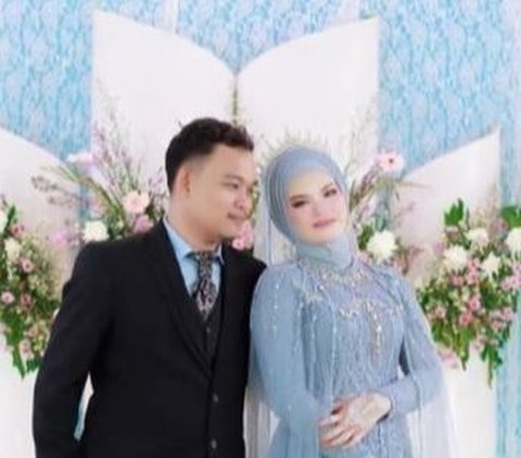 Pasangan ini mengenakan pakaian berbeda saat resepsi pernikahan. Tampak Alya mengenakan baju pengantin warna biru muda. Sedangkan Ryan Dono kenakan setelan jas warna hitam.