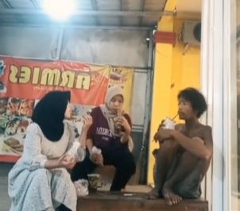 Dalam unggahan tersebut, pemilik akun tampak merekam momen dua orang wanita yang sedang asyik menikmati momen kebersamaan dengan seorang pria ODGJ. Mereka terlihat sedang nongkrong di sebuah warung pinggir jalan.