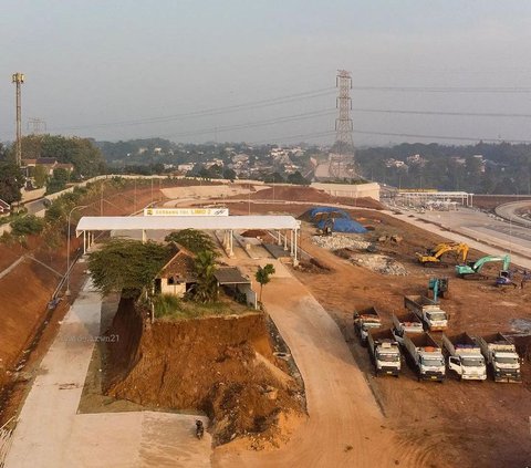 Rumah yang berada tepat di tengah-tengah pintu tol ini terlihat memiliki tinggi tanah yang berbeda. Bangunan tersebut memang berada di atas gundukan tanah yang belum dikeruk oleh alat berat.