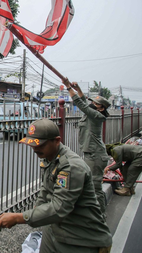 Satuan Polisi Pamong Praja ( Satpol PP ) DKI Jakarta saat menertibkan alat peraga partai politik berbentuk bendera di kawasan Jalan Raya Jakarta-Bogor.