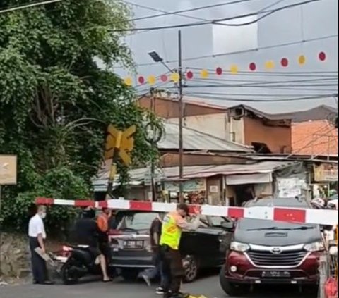 Situasi semakin menegangkan ketika mobil berwarna abu-abu metalik masih berada di tengah perlintasan. Dari arah kanan, kereta api berada di posisi semakin mendekati perlintasan.