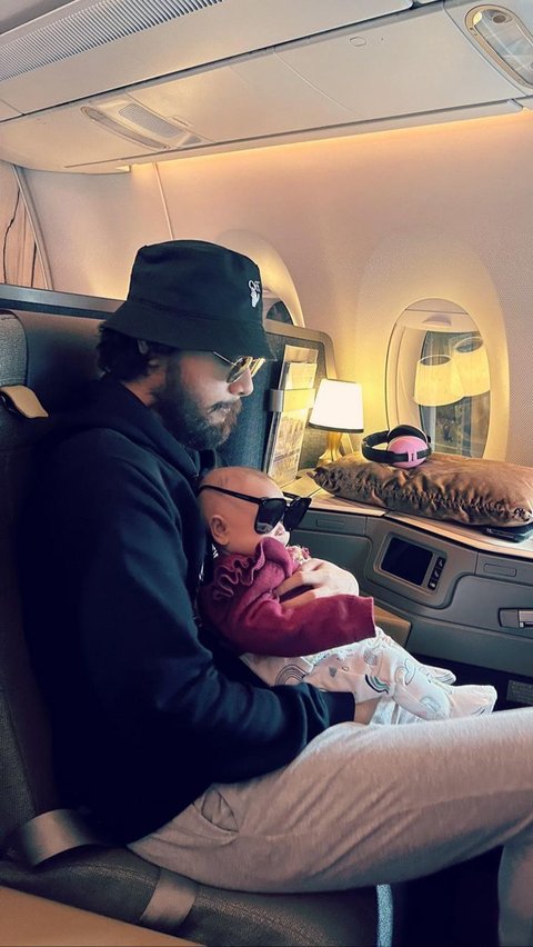 Achmad Megantara tampak menggendong sang anak saat berada di pesawat.
