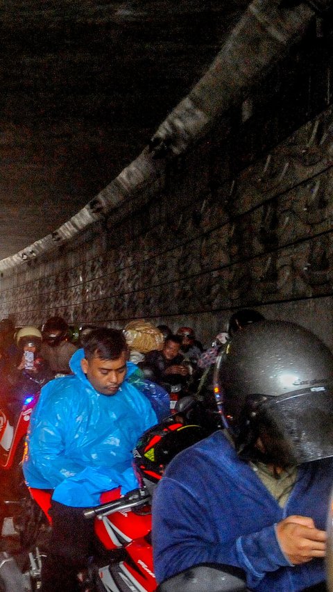 Sejumlah pengendara sepeda motor memanfaatkan waktunya sembari menunggu hujan reda dengan beraktivitas dengan ponselnya di underpass Mampang, Jakarta Selatan, Kamis (06/07/2023).