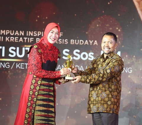 Direktur Konten KLY Wenseslaus Manggut memberikan penghargaan kepada Ketua DEKRANASDA Kota Malang, Widayati Sutiaji dalam Anugrah Inspiratif Liputan6.com kategori perempuan inspiratif pegiat ekonomi kreatif berbasis budaya di Jakarta, Sabtu (8/7/2023).