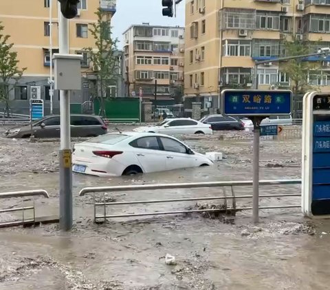 Terjangan banjir memutuskan Jembatan Xiaoqinghe di Distrik Fengtai, Beijing, sehingga membuat beberapa mobil hanyut ke sungai yang arusnya sangat deras.