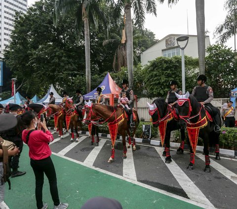 Sejumlah warga dan anak-anak berfoto dengan Polisi Berkuda dari Detasemen Turangga Direktorat Polisi Satwa Polri saat Hari Bebas Kendaraan Bermotor di kawasan Bundaran HI, Jakarta, Minggu (13/8/2023).