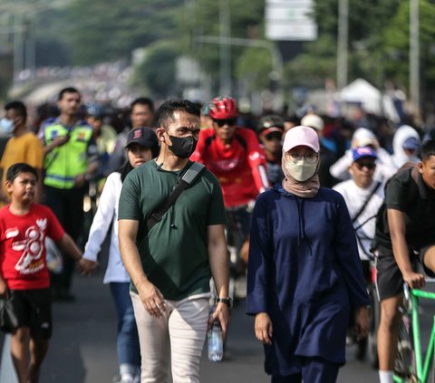 Masyarakat berolahraga menggunakan masker menikmati jalan santai saat car free day (CFD) di kawasan Bundaran HI, Jakarta, Minggu (13/8/2023).