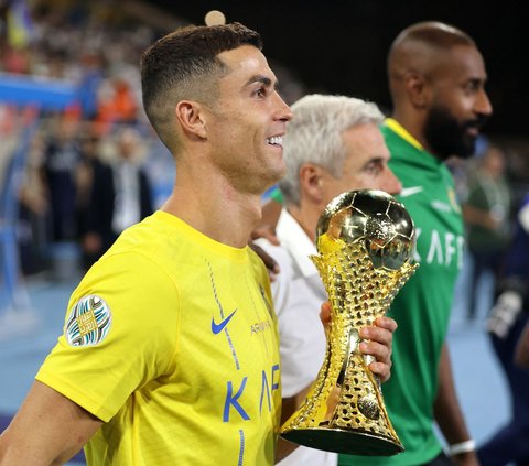 Ekspresi Cristiano Ronaldo yang tersenyum semringah sambil memegang trofi Liga Champions Arab 2023 setelah menjadi pahlawan kemenangan timnya Al Nassr yang sukses meraih juara dalam ajang kejuaraan tersebut.