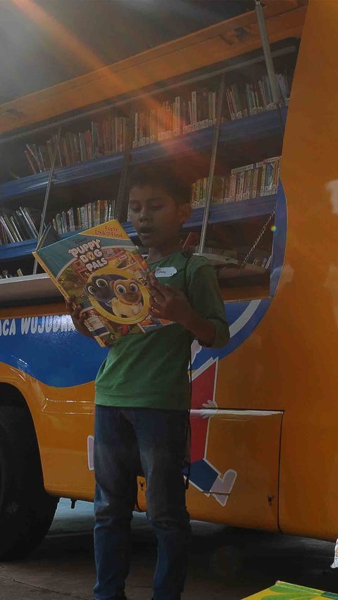 Seorang tampak sedang membaca ragam buku cerita dongeng di depan mobil Perpustakaan Keliling di Taman Menteng, Jakarta, Senin (14/8/2023).