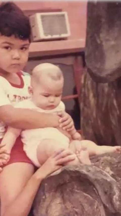 Beginilah potret Dinda Kanyadewi saat kecil. Disana, Dinda kecil terlihat duduk manis bersama kakak kandungnya.