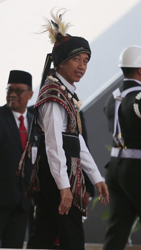 Jokowi tampak mengenakan kemeja putih dengan kain tenun Tanimbar berwarna coklat gelap yang membalut bagian dada dan punggungnya. Selain itu, Presiden juga mengenakan sebuah penutup kepala.