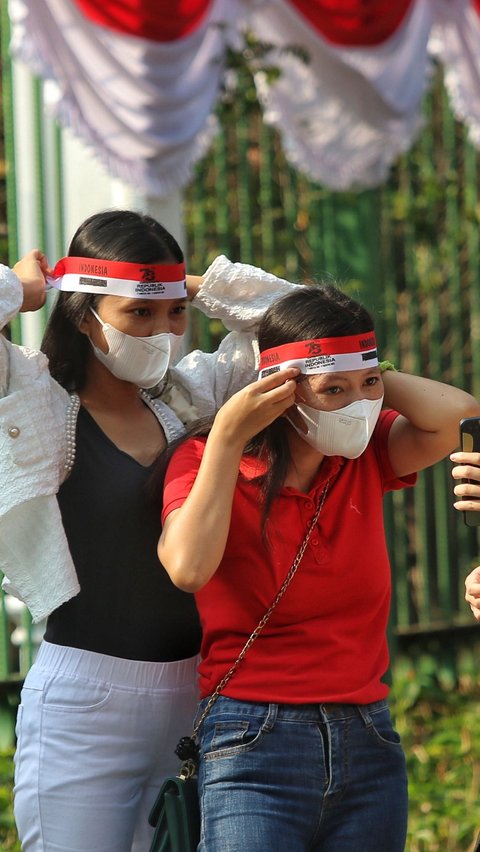 Sejumlah warga terlihat menyiapkan masker untuk dipakai selama mengikuti kirab. Ikat kain merah putih pun juga tak lupa mereka kenakan.