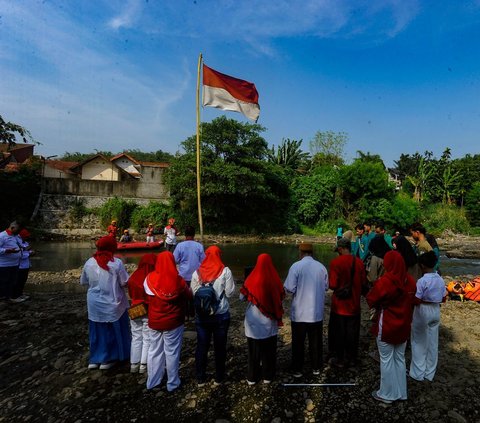 Warga RW 07 saat melakukan pengibaran bendera merah putih pada aliran Sungai Ciliwung yang mengering akibat kemarau panjang di Kedung Halang.