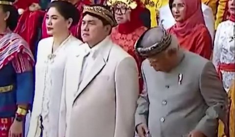 Erick yang sedang serius mengikuti upacara hanya bisa tersenyum sambil mengusap beskapnya usai dijahili Basuki.