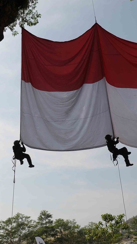 Bendera raksasa itu dikaitkan dengan tali karmantel pada mulut Goa Sigugula di Tebing Arpam, Klapanunggal.