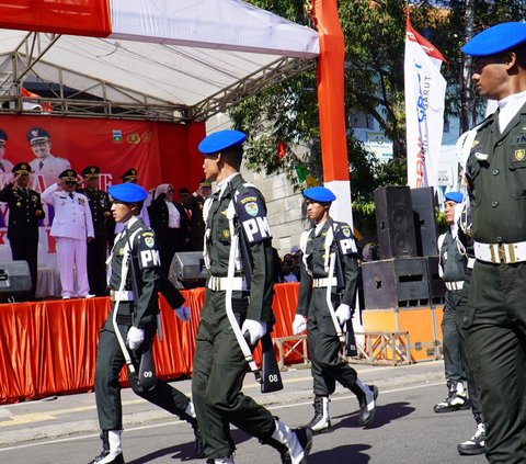 Sejumlah pejabat pemerintah, tokoh masyarakat, dan pelajar berkumpul untuk menghormati bendera Merah Putih yang berkibar dengan gagah.