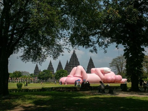 FOTO: Momen KAWS Liburan di Indonesia, Begini Potretnya Saat Asyik Rebahan di Candi Prambanan