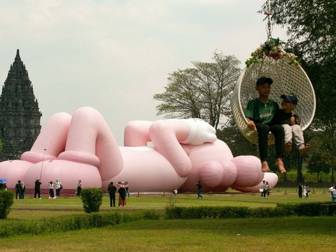 FOTO: Momen KAWS Liburan di Indonesia, Begini Potretnya Saat Asyik Rebahan di Candi Prambanan