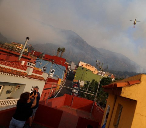 Kondisi itu membuat warga yang tinggal di wilayah Aguamansa mengabadikan momen helikopter pemadam kebakaran yang terbang di atas wilayahnya saat akan memadamkan api yang membakar lahan hutan di Pulau Tenerife, Kepulauan Canary, Spanyol.