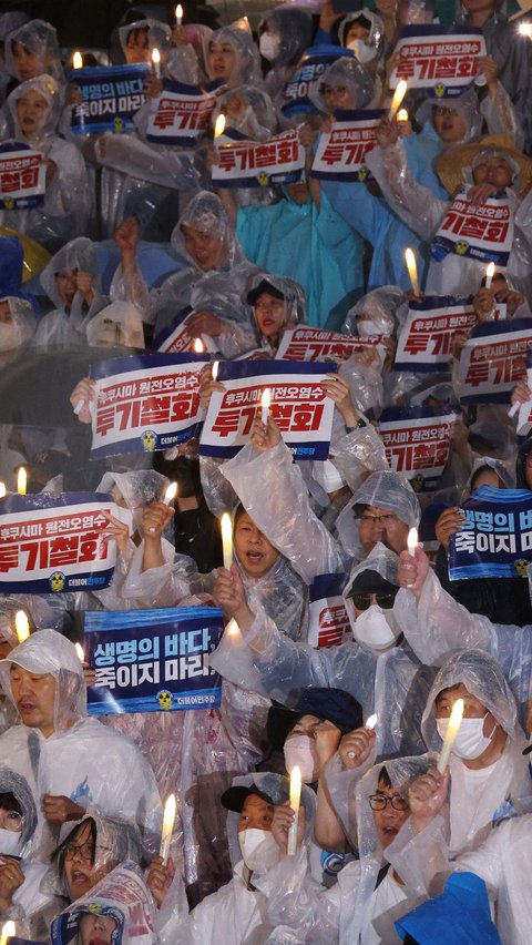 Mereka meneriakkan slogan-slogan saat menyalakan lilin menentang rencana Jepang untuk membuang air limbah olahan dari pembangkit listrik tenaga nuklir Fukushima ke laut, di Majelis Nasional di Seoul.