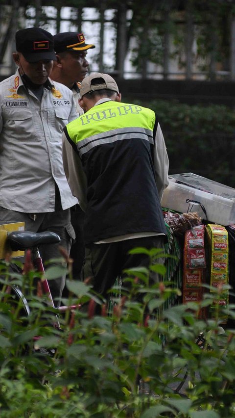 Petugas Satpol PP saat menertipkan pedagang kopi starling di kawasan Bundaran HI, pada Jumat (25/8).