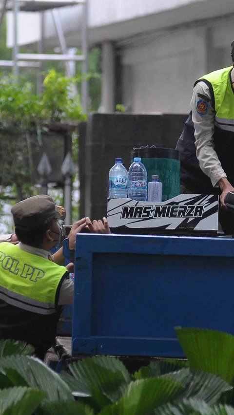 Satpol PP menaikkan sepeda dan barang dagangan pedagang kopi starling ke atas truk.