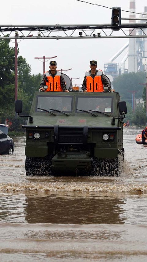 Pasukan tentara China terlihat membelah banjir dengan kendaraan militer serbaguna.