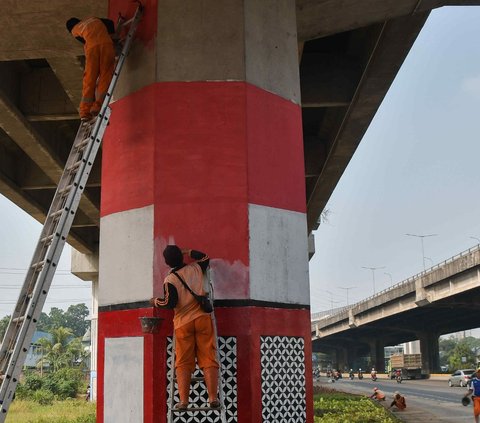 Dua orang petugas Penanganan Prasarana dan Sarana Umum (PPSU) melakukan pembuatan mural bertema kemerdekaan pada tiang penyangga Tol Becakayu (Bekasi Cawang Kampung Melayu) di kawasan Cipinang Besar Selatan, Jakarta, Senin (7/8/2023).