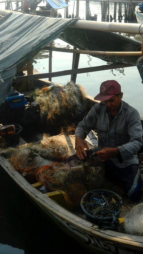 Nelayan memperbaiki jaring usai menangkap rajungan di kampung nelayan Dadap, Tangerang, Selasa (08/08/2023).