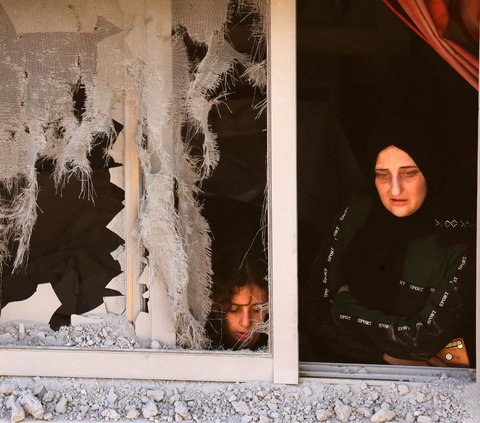 Seorang ibu dengan wajah penuh kecemasan berdiri dekat dengan putrinya saat melihat kondisi luar rumahnya yang berantakan setelah serangan militer Israel di kamp Asker di kota Nablus di Tepi Barat.