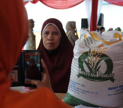 Petugas mengambil gambar seorang warga saat menerima bantuan pangan 10 kilogram beras di Gudang Bulog, Jakarta, Senin (11/9/2023).