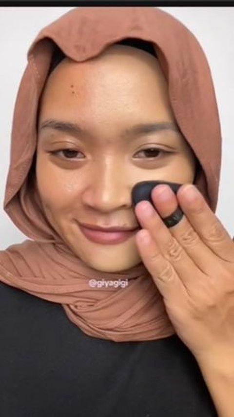 The woman starts the process by using base makeup such as foundation and concealer to cover dark spots on the face.