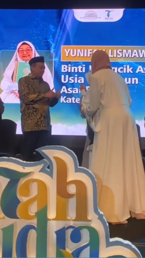 Dua jempol tampak diberikan oleh salah seorang ustaz saat Yuni berhasil sampai di tengah panggung. Simbol tangan ini seolah memberikan selamat atas pencapaian Yuni yang terus berusaha menghafal Al-Quran meski kondisinya sempat kritis.