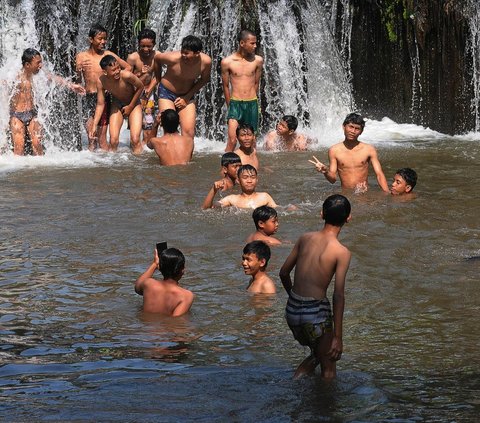 Debit aliran Kalimalang yang turun dari batas normal dimanfaatkan oleh sebagian anak untuk bermain air sepulang sekolah, pada Jumat (15/9/2023). Kondisi ini juga didukung oleh cuaca panas yang belakangan terjadi.