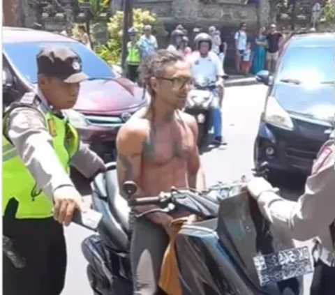 Sebuah video yang diunggah akun Instagram @lowslow.indonesia merekam saat seorang turis asing yang mengendarai motor dengan tak menggunakan helm dan telanjang dada mengamuk saat diberhentikan polisi.