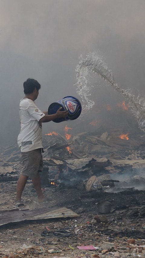 Seorang warga berusaha menggunakan ember berisi air saat melakukan pemadaman api yang membakar lokasi permukiman semi permanen di Bintara Jaya.
