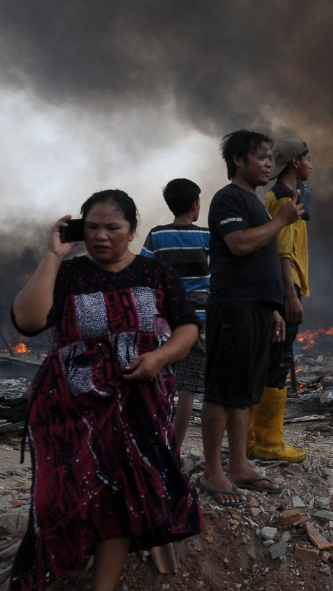 Seorang warga tampak sedang menghubungi keluarganya saat musibah kebakaran di kawasan permukiman semi permanen dan lapak barang bekas di Bintara Jaya, Bekasi.