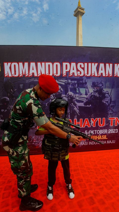 Seorang anak mencoba memegang senapan serbu  yang ditampilkan dalam pameran tersebut.