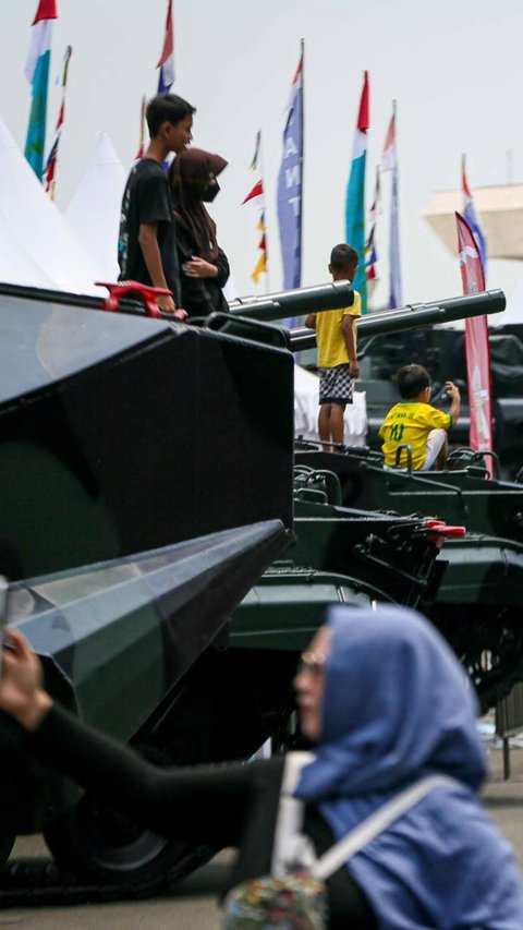 Sejumlah warga berfoto di atas kendaraan milik TNI saat pameran alutsista di kawasan Monas, Jakarta, Minggu (24/9/2023).