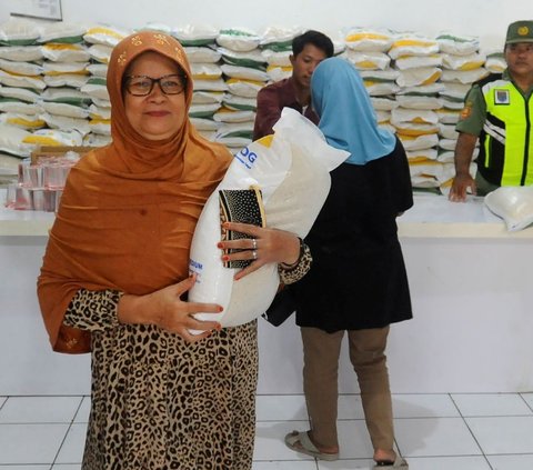 Seorang warga tersenyum usai mengambil beras bantuan sosial (Bansos) dari Perum Bulog di Kantor Kelurahan Meruyung, Depok, Jawa Barat, Selasa  (26/9/2023).