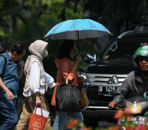 Pejalan kaki menggunakan payung untuk menghindari panas terik matahari yang menyengkat di kawasan Kuningan, Jakarta, Selasa (26/9/2023).