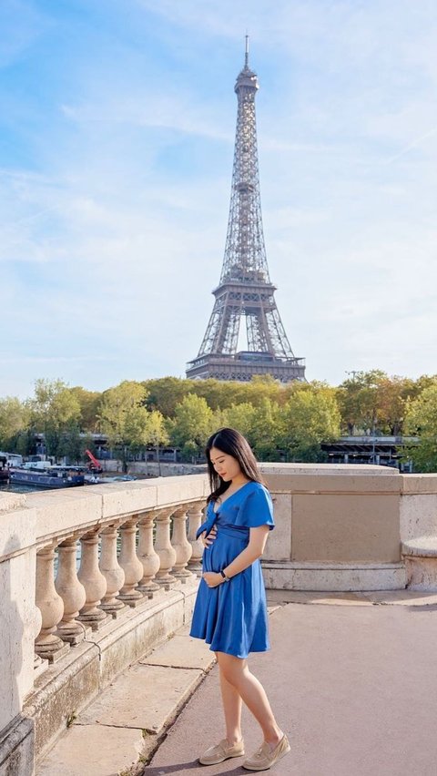 Berbalut dress biru, Valencia berpose dengan latar menara Paris.
