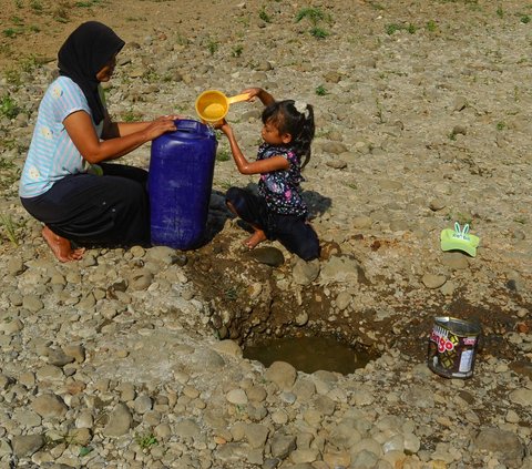 Seorang anak bersama ibunya mengambil air pada galian sumur di tengah aliran Sungai Cihoe, Kamis (28/9/2023). Warga Desa Sukagalih, Jonggol, Bogor, mengalami kesulitan air bersih di tengah fenomena El Nino yang menyebabkan musim kemarau berkepanjangan.