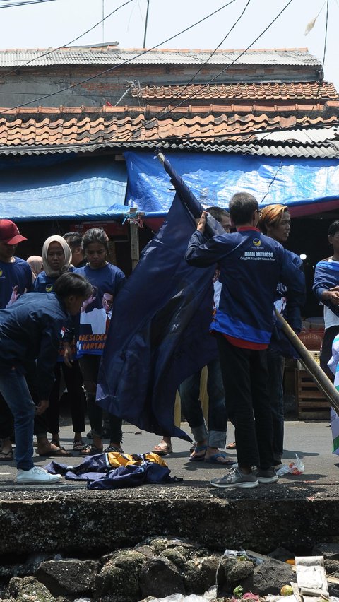 Sebelum dibakar, massa mencopoti atribut Partai NasDem berupa bendera yang menghiasi sepanjang jalan depan pasar tersebut.