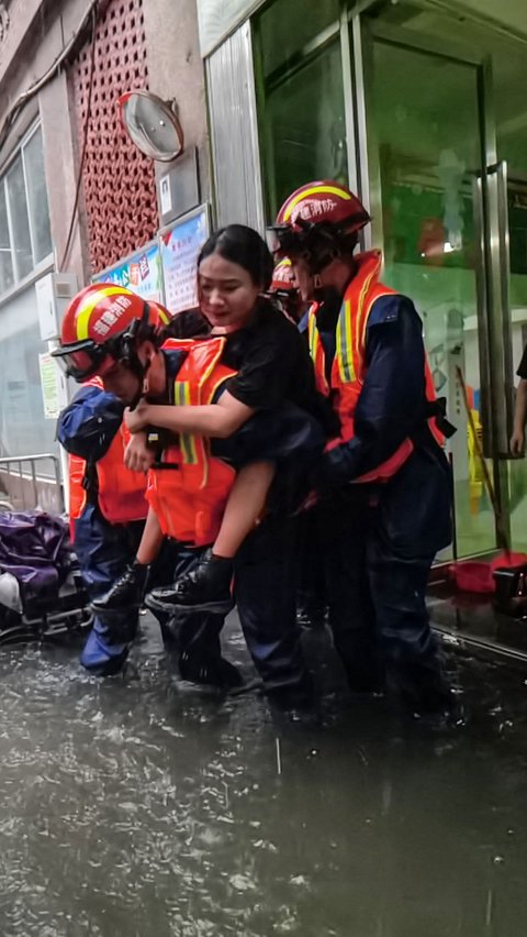 Foto yang diambil pada (4/9/2023) menunjukkan tim penyelamat sedang mengevakuasi seorang wanita dari rumahnya saat banjir yang disebabkan oleh Topan Haikui melanda Kota Xiamen di Provinsi Fujian.
