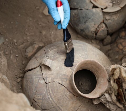 Seorang arkeolog membersihkan benda bejana keramik yang ditemukan di samping mumi berusia 1.000 tahun di situs arkeologi di lingkungan perumahan, di Lima, Peru (6/9/2023).